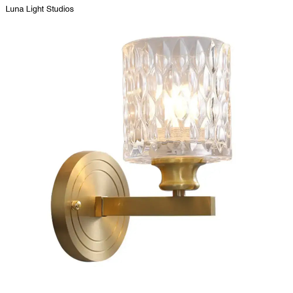 Contemporary brass cylindrical wall light with faceted clear dimpled glass shade for bedroom lighting