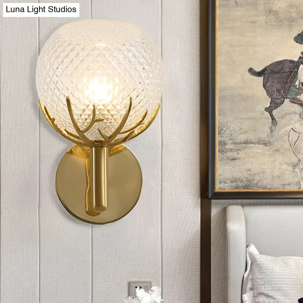 Contemporary brass wall lamp with frosted lattice glass globe and gold-toned antler-inspired metal arms for bedroom sconce