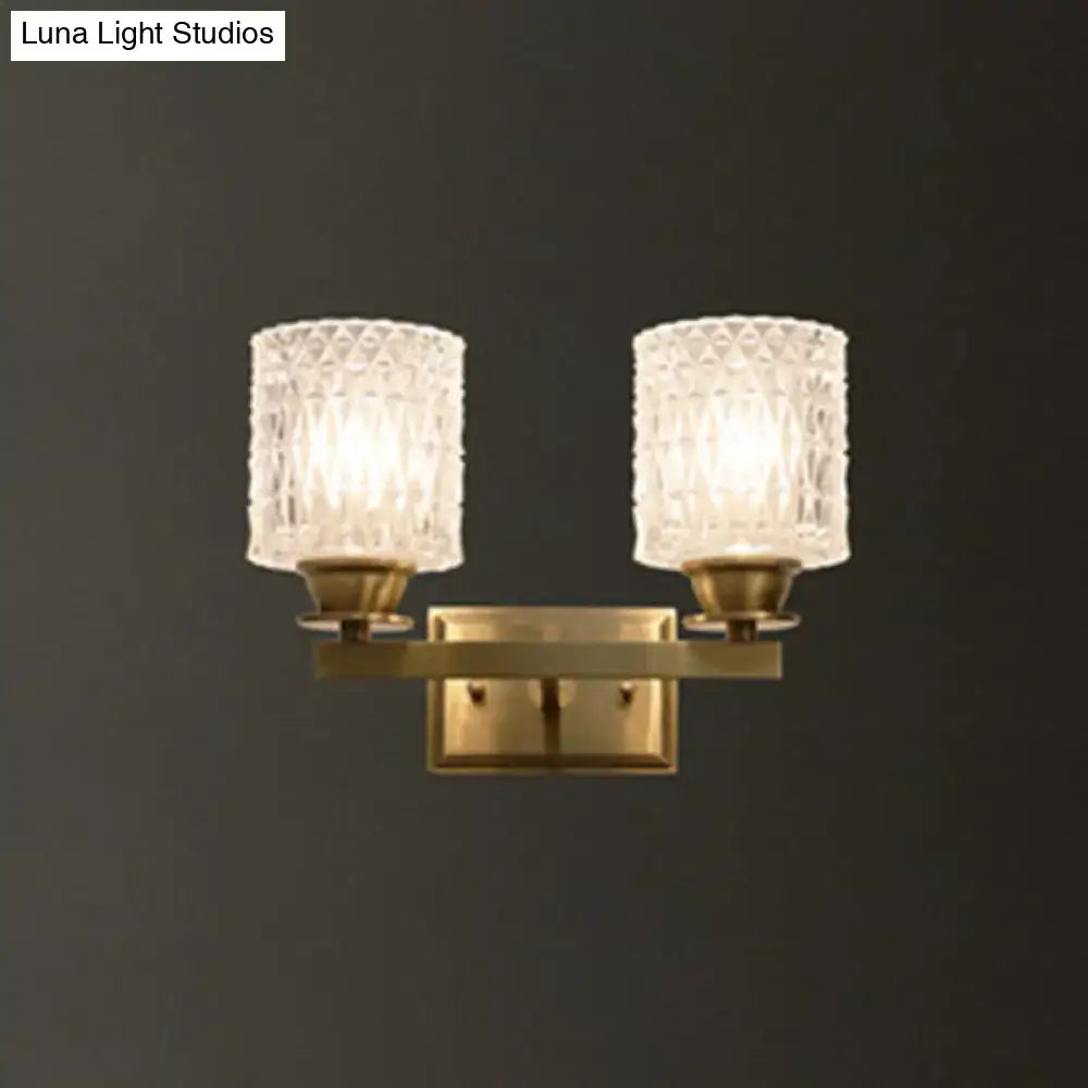 Brass-finished contemporary wall light with two textured clear glass shades direct wired electric power source