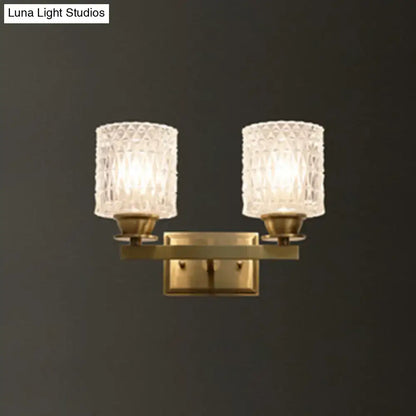 Brass-finished contemporary wall light with two textured clear glass shades direct wired electric power source