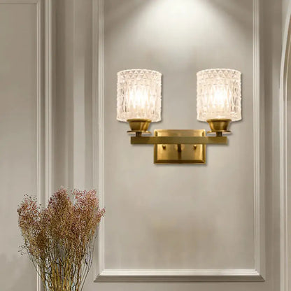 Contemporary brass-finished wall light with direct wired electric power source and frosted lattice glass shades