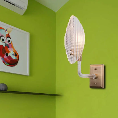 Contemporary brass leaf wall light fixture with a translucent glass sconce and brass-finished mounting plate for living room