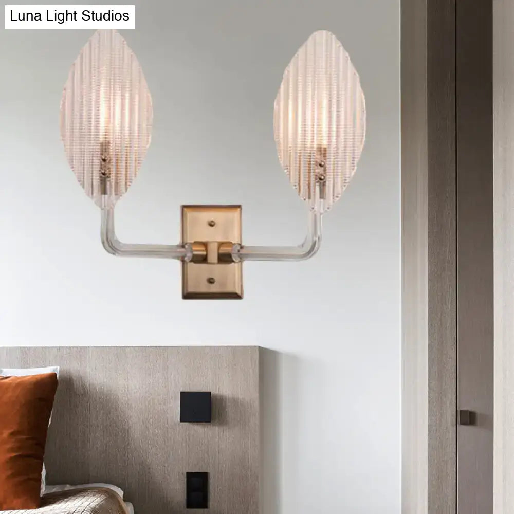 Contemporary brass leaf wall light fixture with two ribbed glass shades and clear acrylic arm for living room use