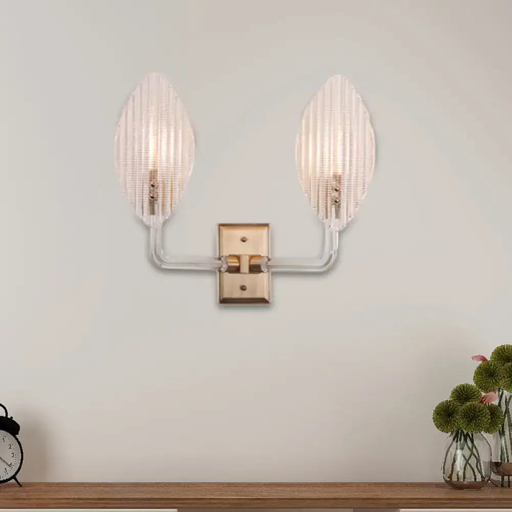 Contemporary brass leaf wall light fixture with clear ribbed glass shades and curved arms for living room use