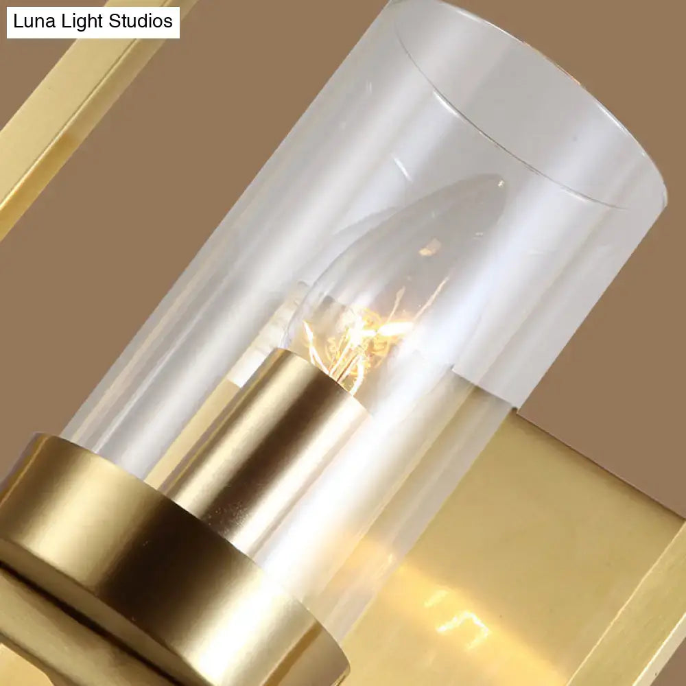 Contemporary brass wall light with a gold-toned light fixture and clear glass cylinder shade for bedroom use