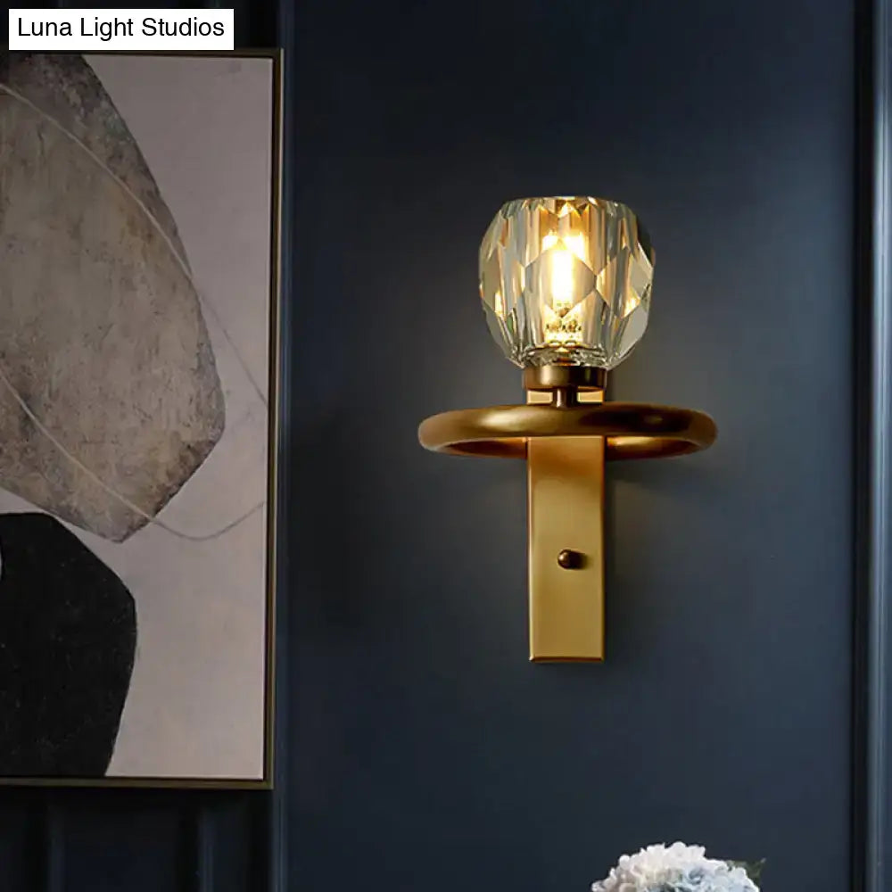 Contemporary brass wall sconce with gold-toned finish and global crystal shade featuring a faceted crystal bulb for dining room use