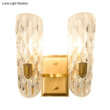 Contemporary brass water glass wall sconce with gold finish and textured clear water glass shades for bedroom bedside light