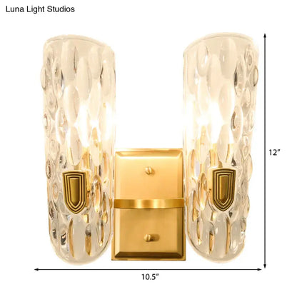 Contemporary brass wall sconce with gold finish and clear water glass shades featuring hammered texture for bedroom use