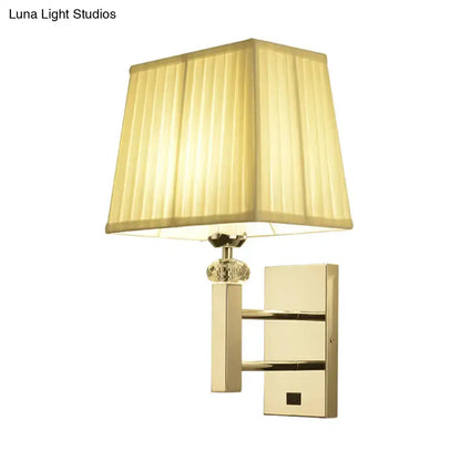 Contemporary gold-toned wall sconce light fixture with cream pleated lampshade crystal accent and spot light feature