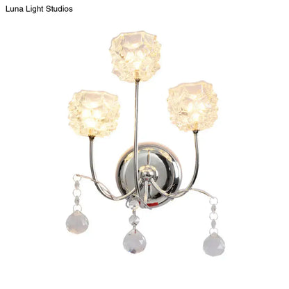 Contemporary chrome wall sconce with three faceted crystal shades and dangling teardrop crystals featuring fixture height