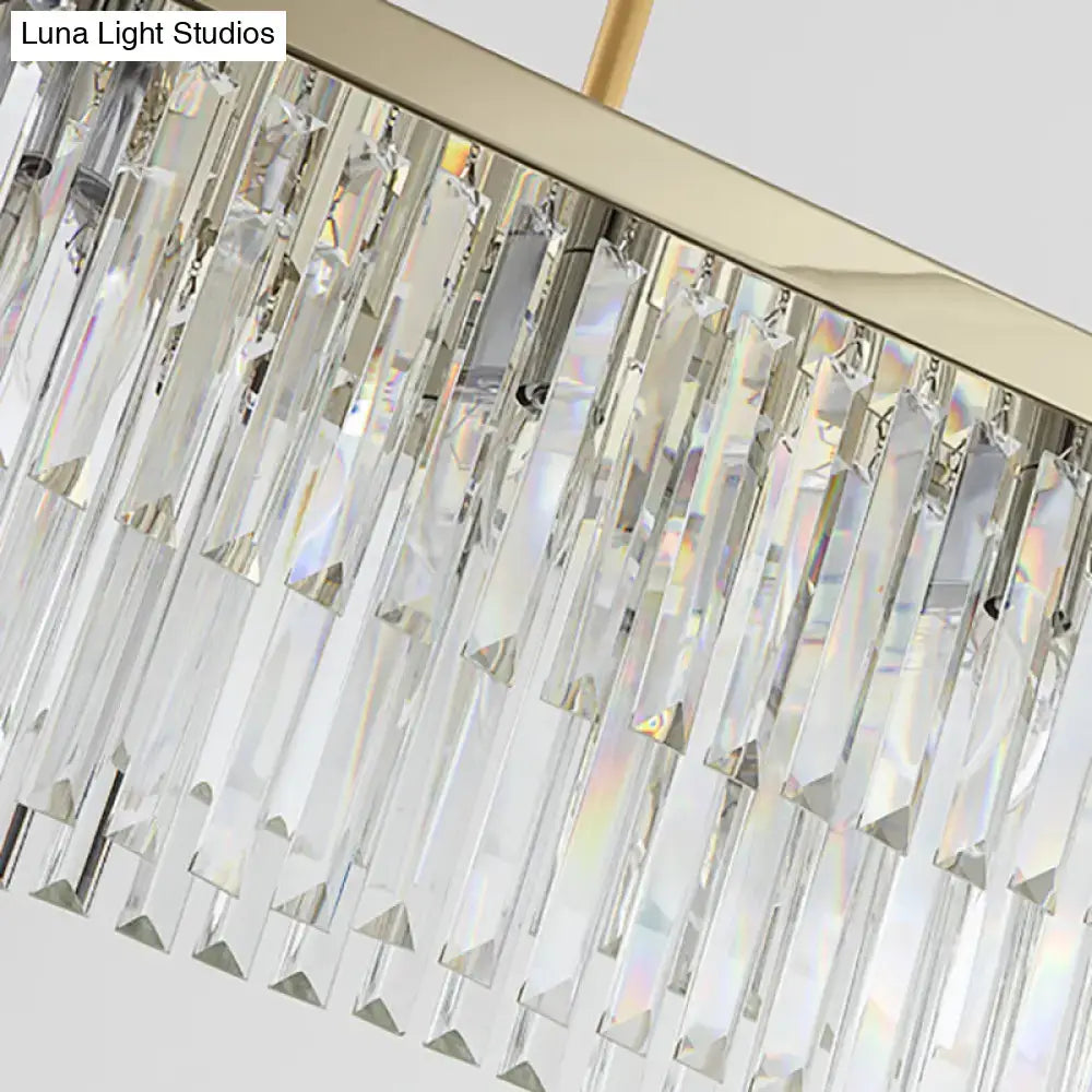 A modern dining room chandelier light fixture with clear amber crystal prisms and a gold-toned frame