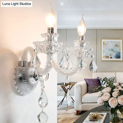 Contemporary crystal chandelier-style wall sconce with silver base and clear faceted crystals for living room lighting