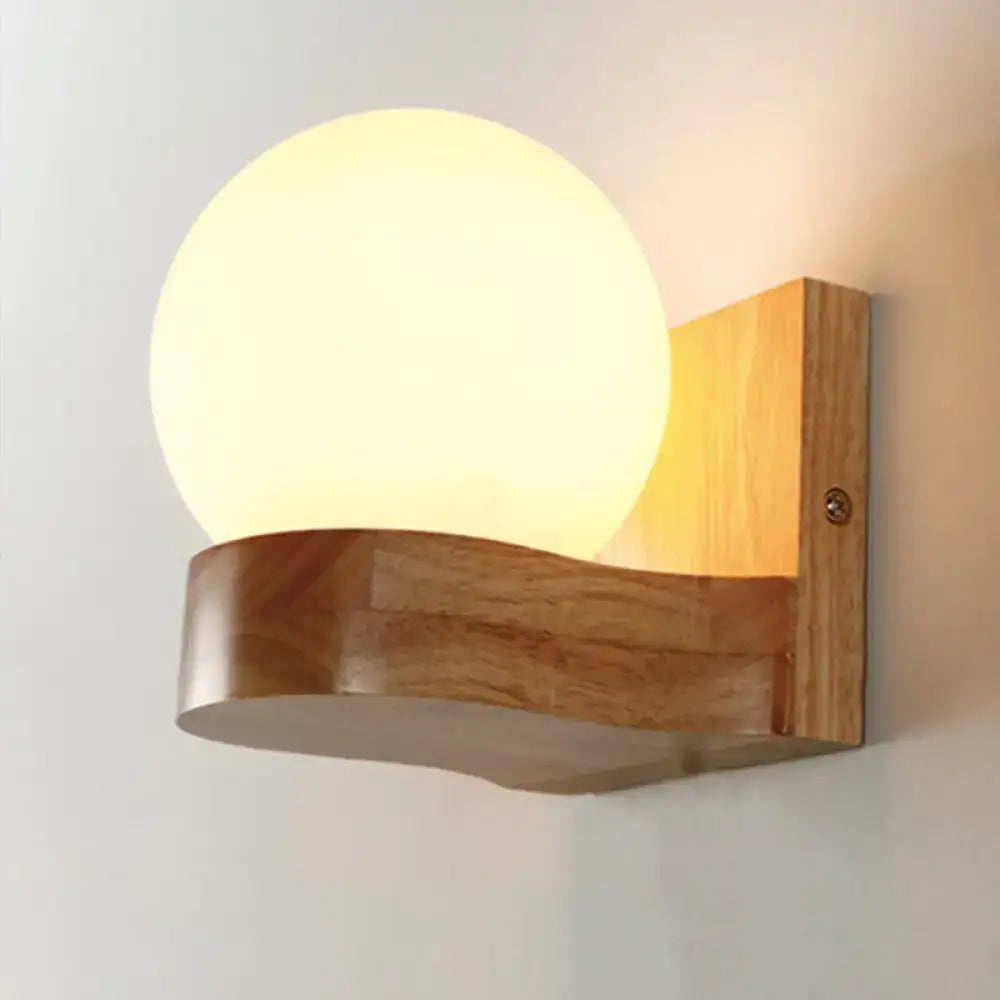 Contemporary cream glass sconce light fixture with warm-toned spherical lamp and wooden base for living room wall