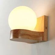 Contemporary cream glass sconce light fixture with warm-toned spherical lamp and wooden base for living room wall
