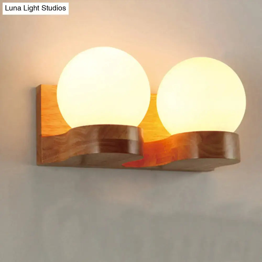 Contemporary cream glass wood sconce light fixture with dual frosted globes and natural wood base for living room wall