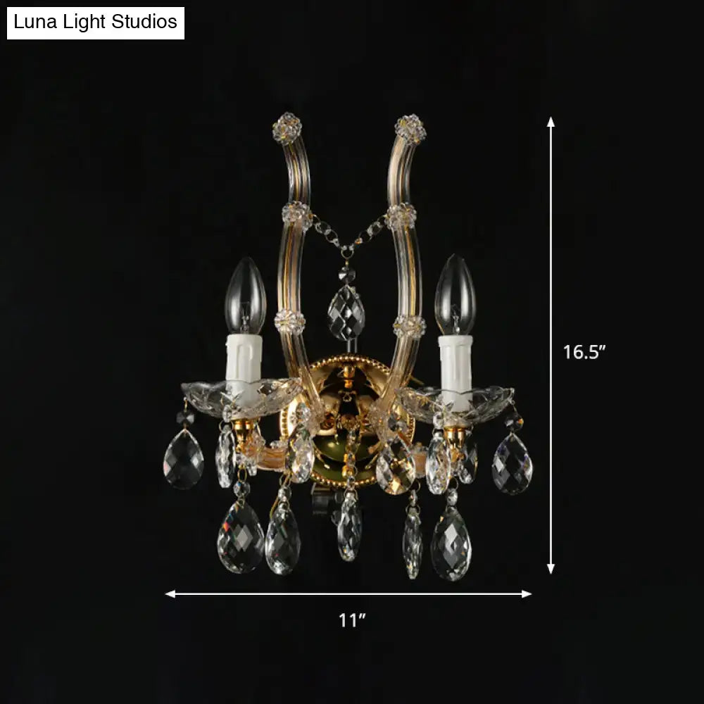 Elegant gold-toned crystal deco wall sconce with amber glass and candle bulbs featuring a fixture width suitable for bedrooms