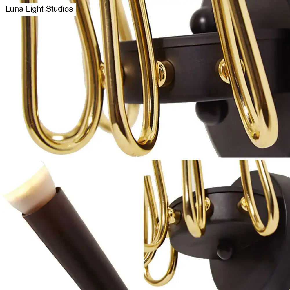 Contemporary metal sconce featuring gold-toned curved arms and a matte black base for living room lighting