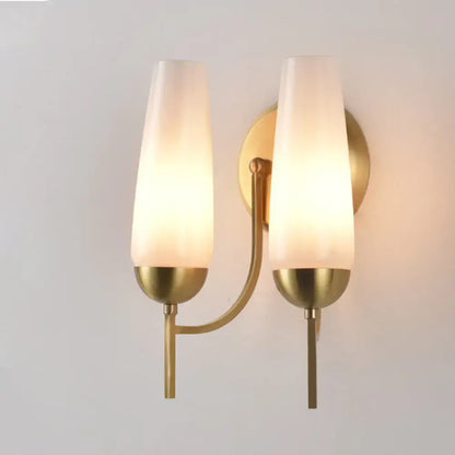 Contemporary gold and opal conical wall sconce with brass finish and two frosted glass shades for bedroom lighting