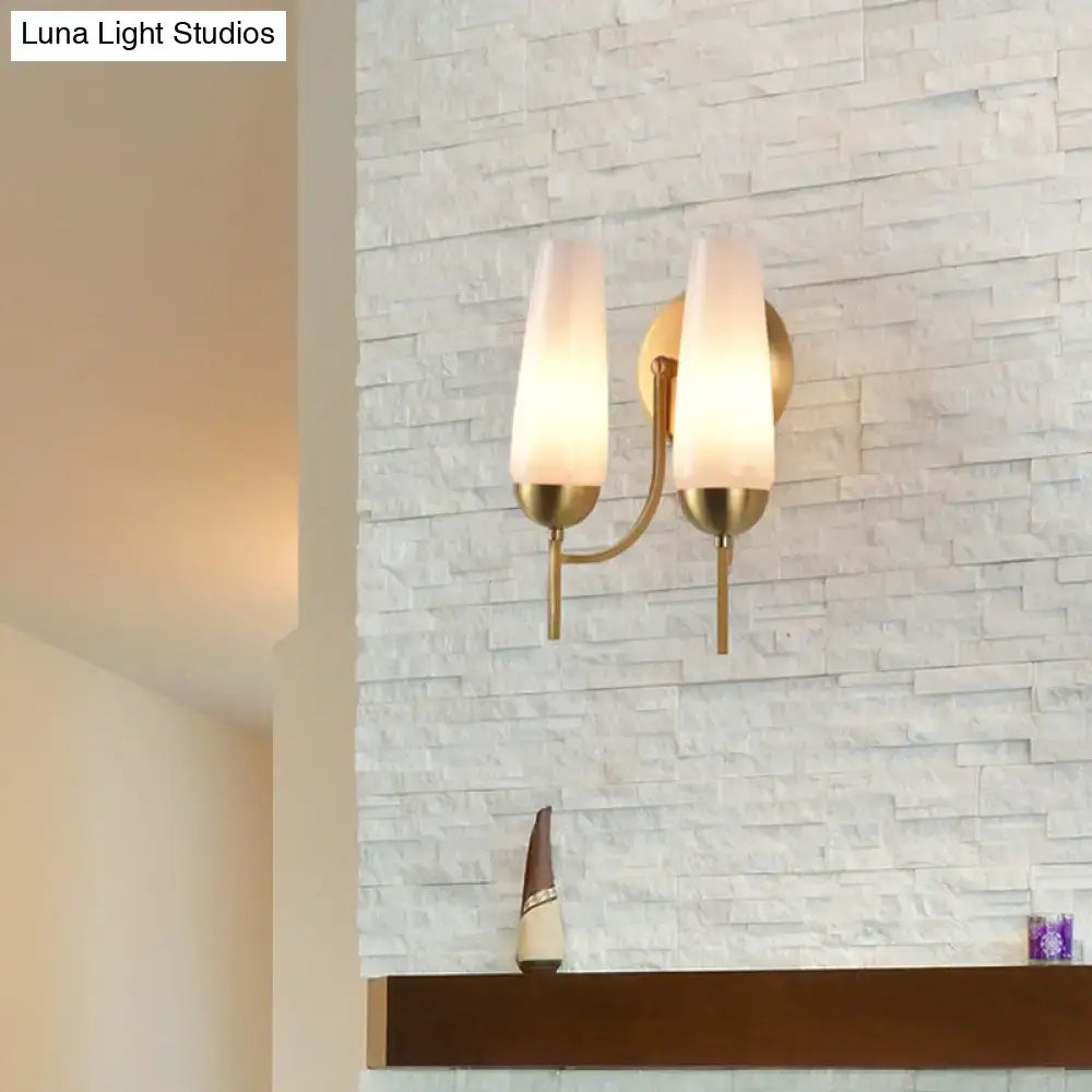 Contemporary gold and opal conical wall sconce with a brass finish and two frosted glass shades for bedroom lighting