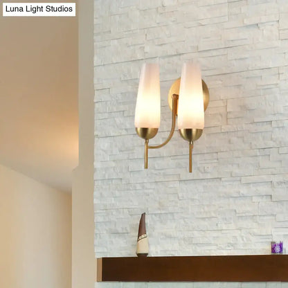 Contemporary gold and opal conical wall sconce with a brass finish and two frosted glass shades for bedroom lighting