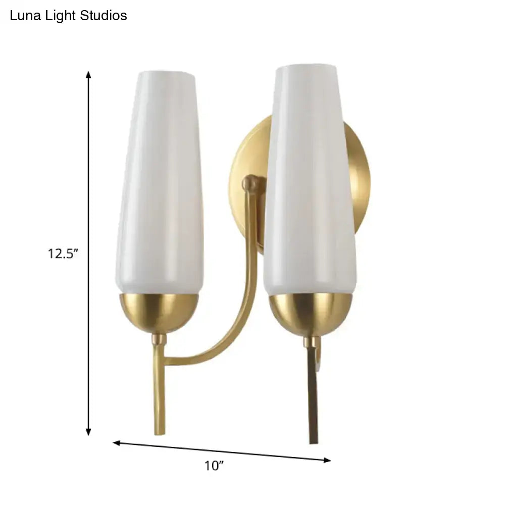 Contemporary gold-toned wall sconce with two frosted white opal glass shades for bedroom lighting