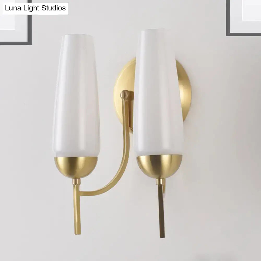 Contemporary gold-toned wall sconce with two frosted white glass opal conical shades for bedroom lighting