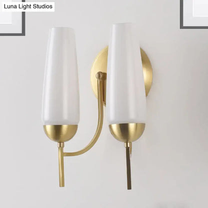 Contemporary gold-toned wall sconce with two frosted white glass opal conical shades for bedroom lighting