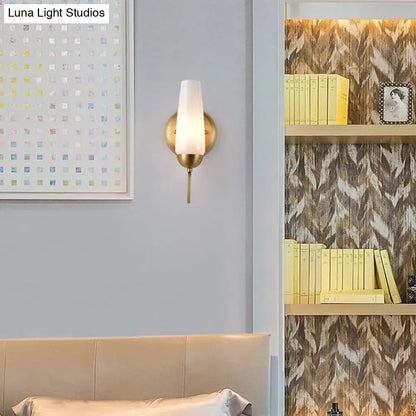 Contemporary gold-toned wall sconce with opal frosted glass shade for bedroom lighting