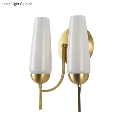 Contemporary gold-toned wall sconce with two frosted white cylindrical shades for bedroom lighting