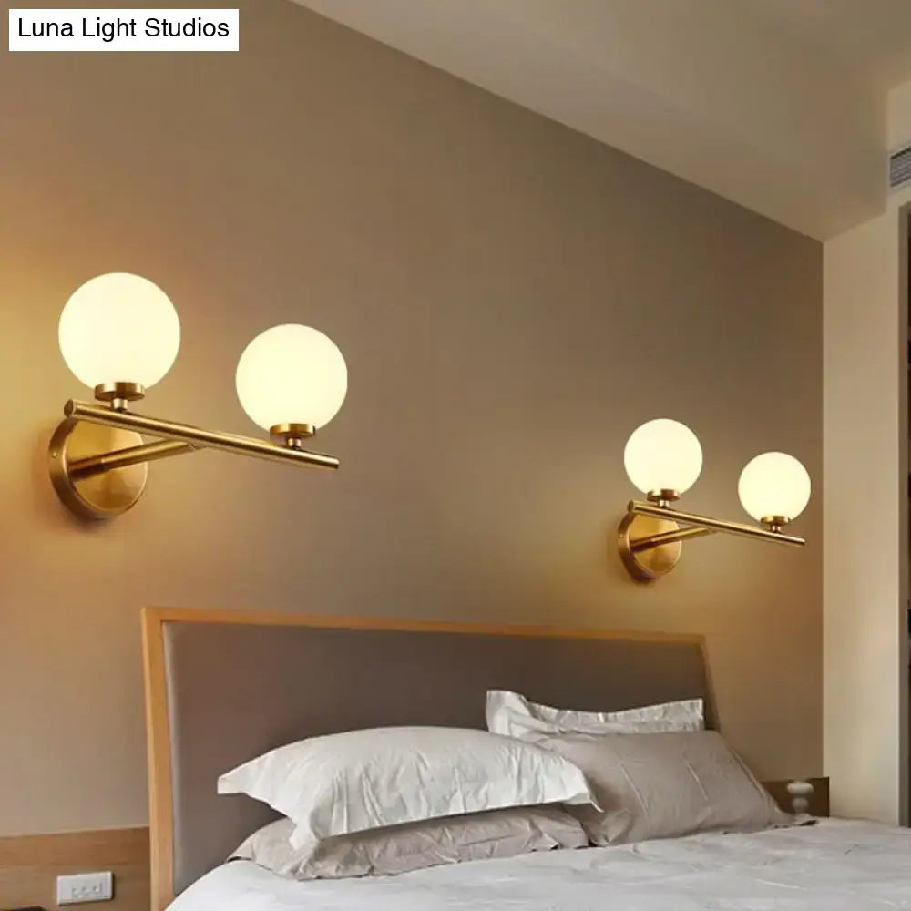 Contemporary gold wall light fixture with frosted white glass globe shades suitable for e12 bulb use