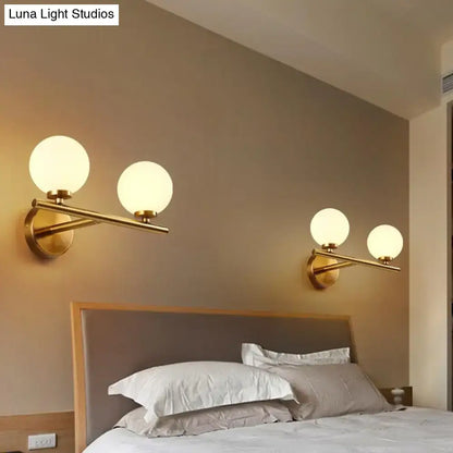Contemporary gold wall light fixture with frosted white glass globe shades suitable for e12 bulb use