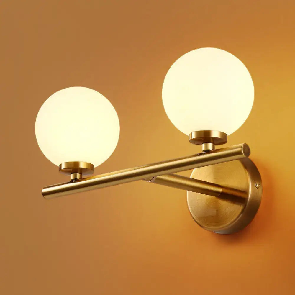 Contemporary brass-finished wall light with two frosted glass globes e12 fixture height ideal for bedroom use