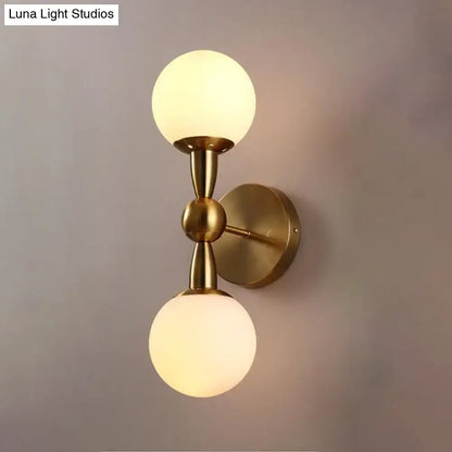 Contemporary brass-finished wall light fixture with two frosted white glass globe shades e12 fixture height