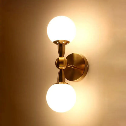 Contemporary brass-finished wall light with two frosted glass globes e12 fixture for bedroom wall lighting