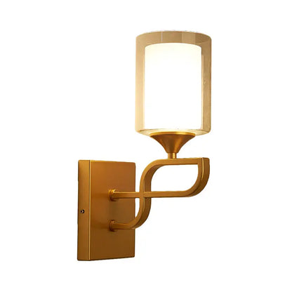 Contemporary gold armed sconce light with cylindrical frosted opal glass shade and curved metal arm for bedroom use