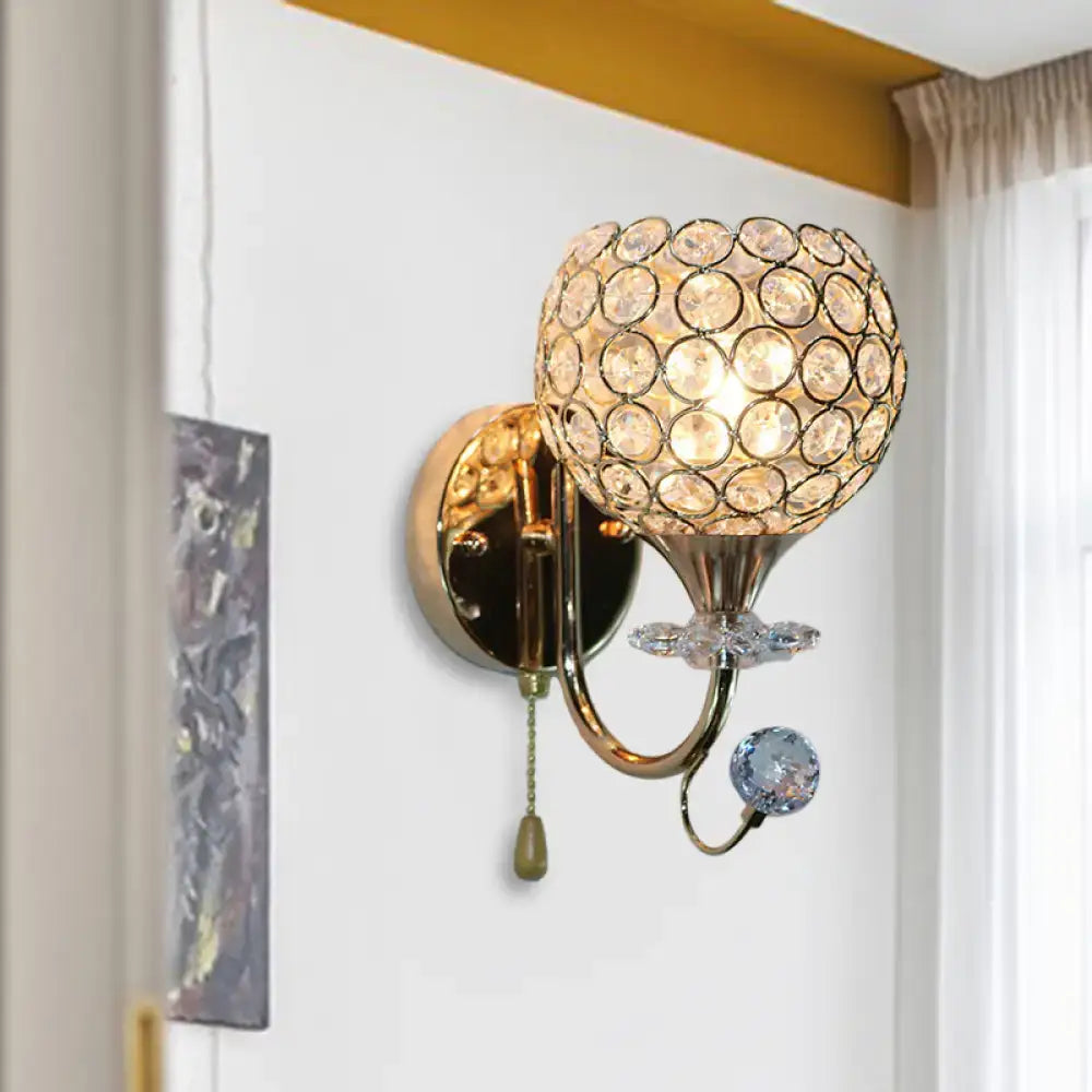 Contemporary gold-toned living room wall sconce with beveled glass globe and dangling faceted glass orb