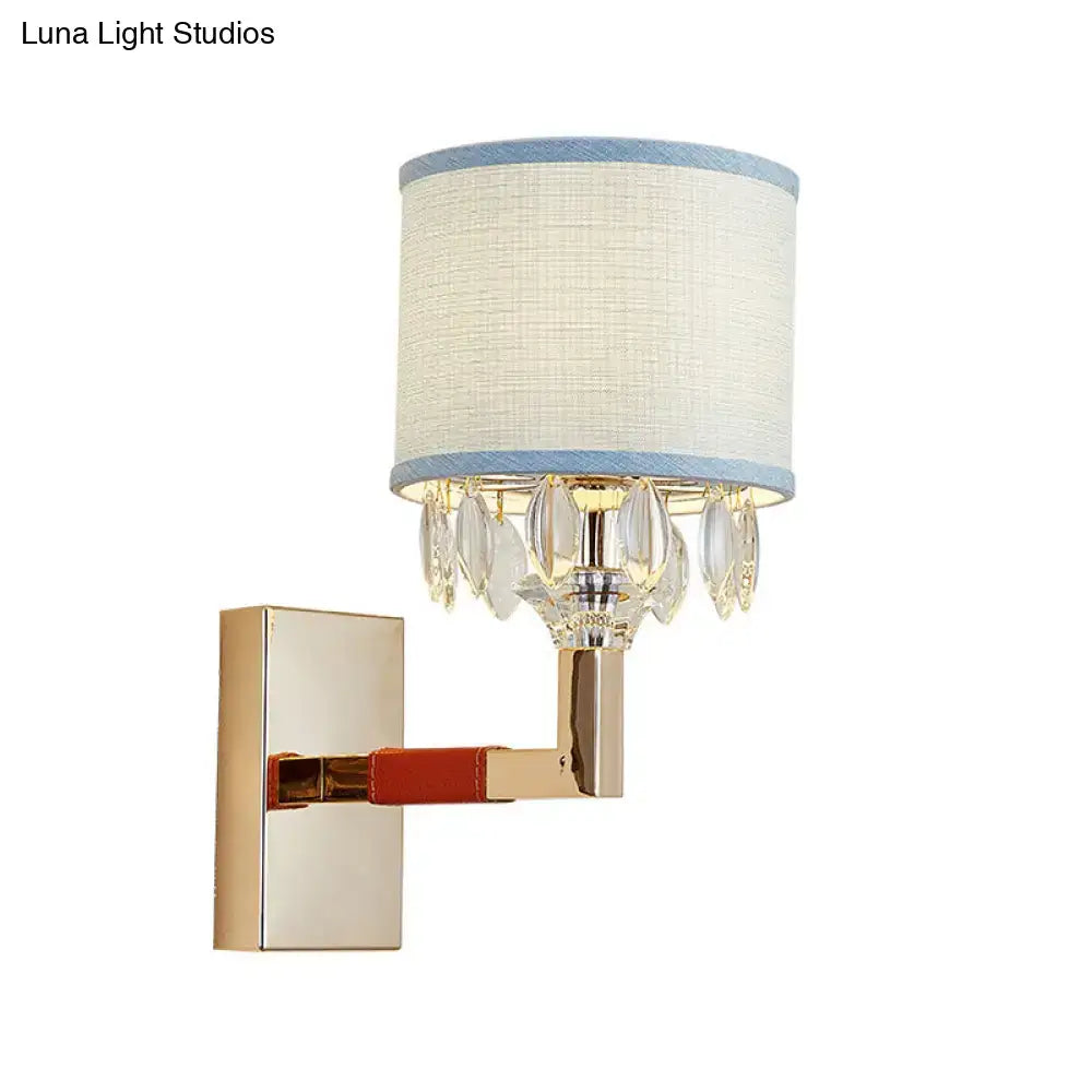 Contemporary gold wall light with crystal deco droplets and off-white drum fabric shade trimmed in light blue for bedroom