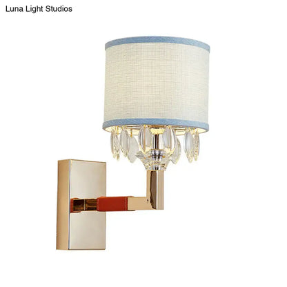 Contemporary gold wall light with crystal deco droplets and off-white drum fabric shade trimmed in light blue for bedroom