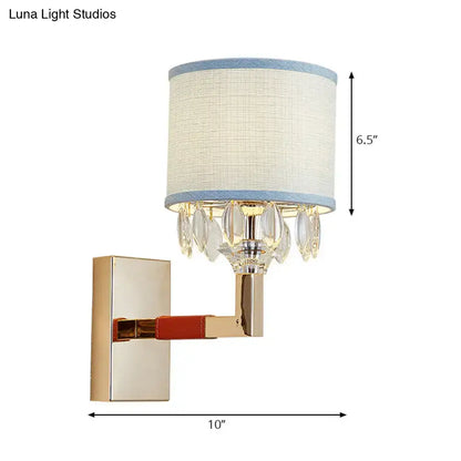 Contemporary gold wall light with drum fabric shade and blue crystal deco accents for bedroom decor