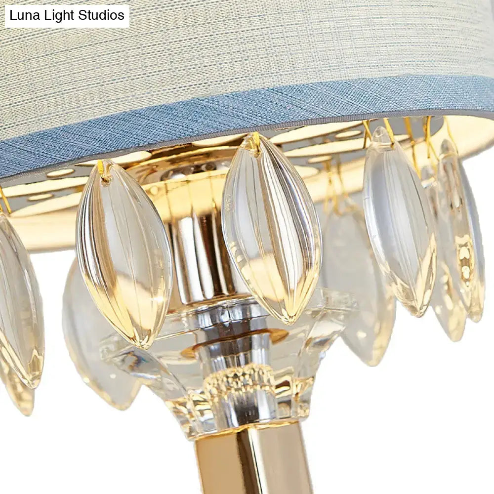 Elegant gold wall light featuring crystal deco teardrop droplets and a light blue drum fabric shade for bedroom use