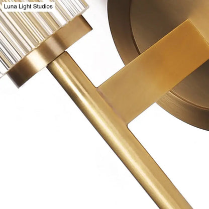 Contemporary gold brass wall light fixture with cylindrical ribbed glass shade and geometric metal arms for bedroom use