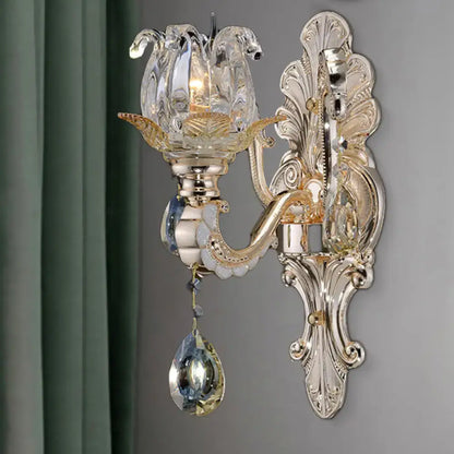 Elegant gold-toned wall lamp with crystal drop lotus design featuring dangling teardrop crystals for bedroom light fixture