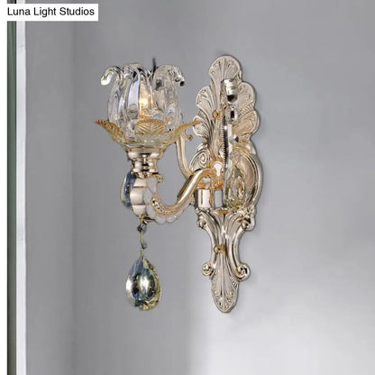 Elegant gold-toned wall lamp with crystal drop featuring a clear flower-shaped shade for bedroom light fixture use