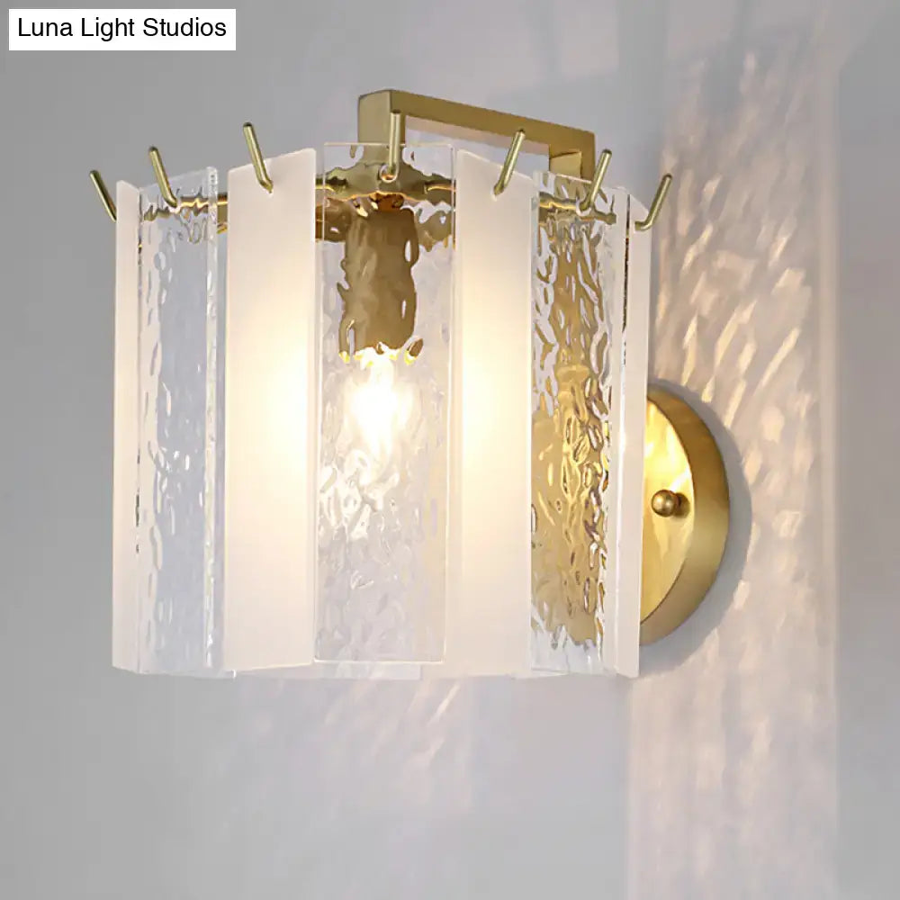 Contemporary gold drum wall sconce light with textured glass panels and integrated hooks for bedroom use