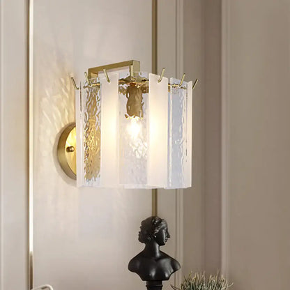 Contemporary gold drum wall sconce light with textured white glass panels and decorative hooks for bedroom use