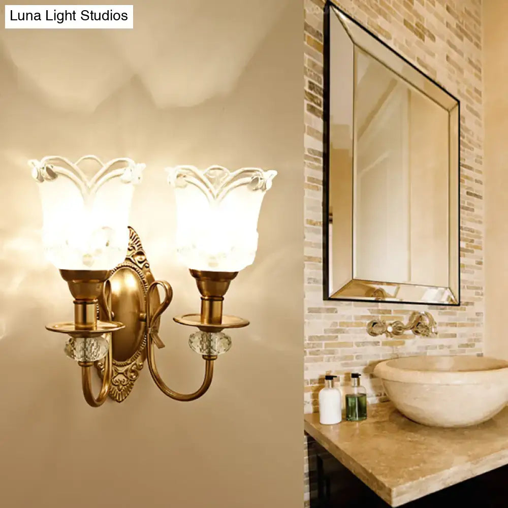 Antique brass two-light wall lamp with frosted glass petal shades and crystal accents for bedroom decor