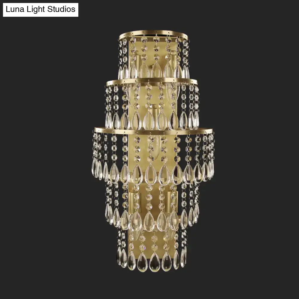 Contemporary gold layered bedside wall lamp featuring a tiered crystal design with teardrop crystals and metal frames