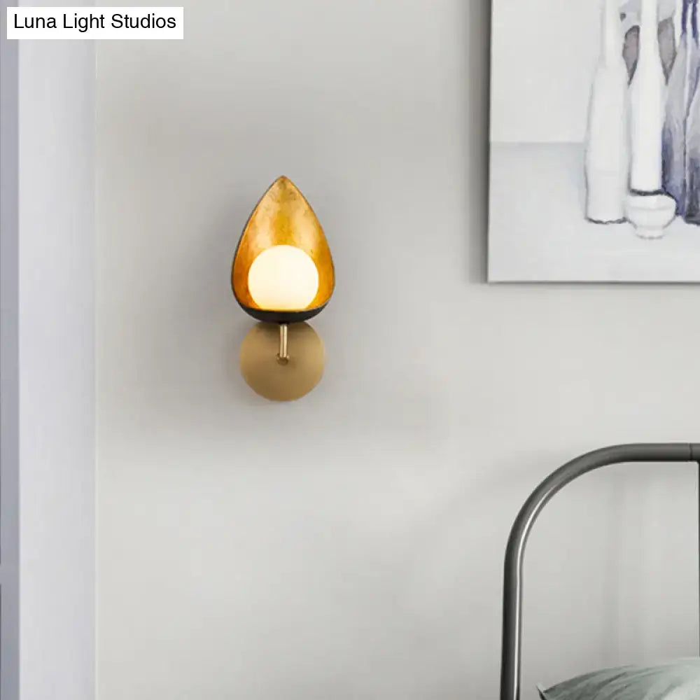 Contemporary gold teardrop sconce light with warm amber glass shade and brass metal base for bedroom use