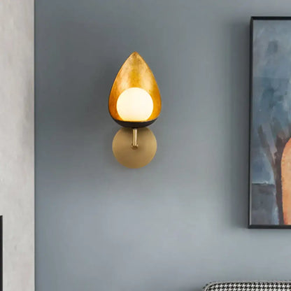 Contemporary gold teardrop sconce light with frosted glass bulb and circular base ideal for bedroom lighting