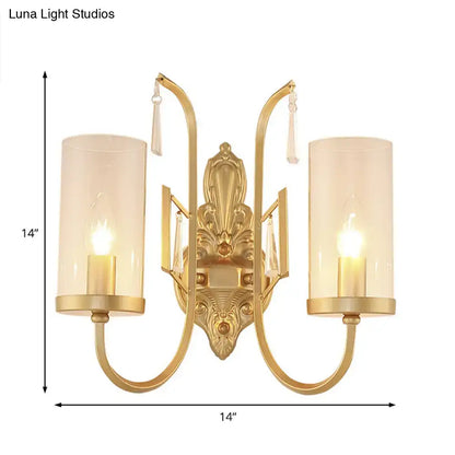 Contemporary gold wall light bedroom sconce with two cylindrical clear glass shades and ornate crystal accents